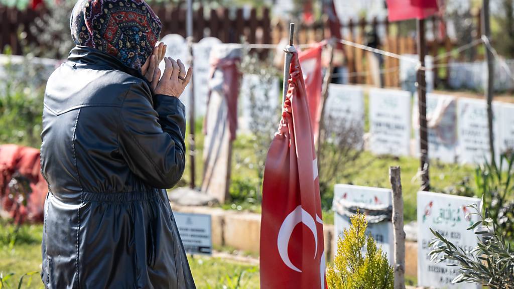 Eine Frau betet am Grab ihrer beim Erdbeben getöteten Familienmitglieder auf einem Gräberfeld am Rande von Adiyaman in der Türkei. Kurz vor dem ersten Jahrestag der Erdbebenkatastrophe kommen hunderte Angehörige zu den Gräbern ihrer Angehörigen, die bei dem Beben gestorben waren. Foto: Boris Roessler/dpa