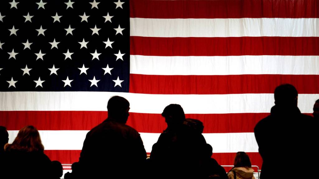 ARCHIV - Menschen stehen am 22.05.2005 auf der Air Base in Ramstein (Rheinland-Pfalz) vor der US-amerikanischen Flagge. Foto: Frank May/dpa