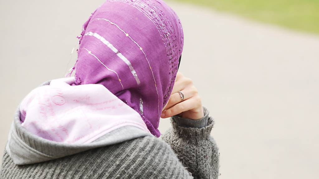ARCHIV - Eine junge Frau mit Kopftuch sitzt an einem Weg. Am Donnerstag hatte der Europäische Gerichtshof (EuGH) vor dem Hintergrund von zwei Streitfällen in Deutschland entschieden, dass ein Kopftuchverbot gerechtfertigt sein kann. Diese Entscheidung verurteilt die Türkei. Foto: Wolfram Steinberg/dpa