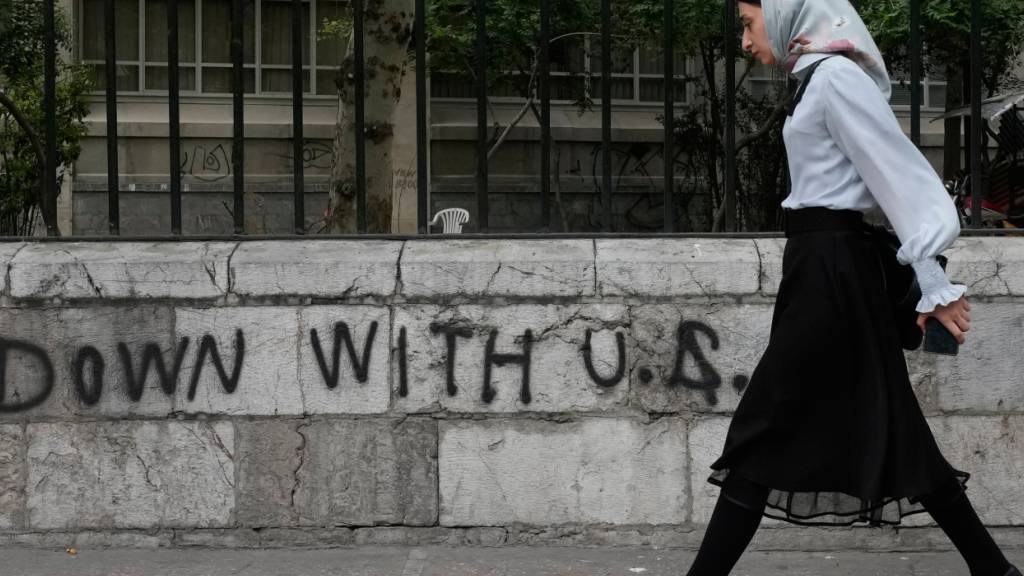 ARCHIV - Eine Frau geht an einem Anti-US-Graffiti vorbei, das an die Wand einer Universität im Zentrum von Teheran gemalt wurde. Foto: Vahid Salemi/AP/dpa/Symbolbild