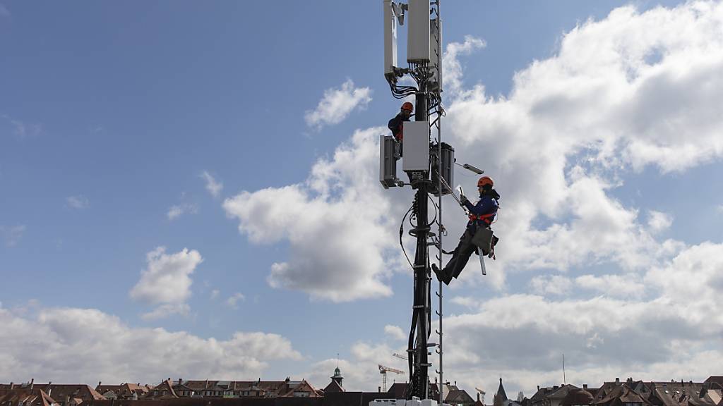 Zwei Fachmänner installieren in Bern im Auftrag der Swisscom eine 5G-Mobilfunkantenne. (Archivbild)