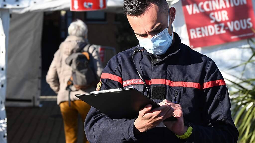 Ein Feuerwehrmann mit Mund-Nasen-Bedeckung steht vor einer Feuerwehrwache im französischen Vailhauquès, die in ein temporäres Corona-Impfzentrum umgewandelt wurde. Foto: Pascal Guyot/AFP/dpa