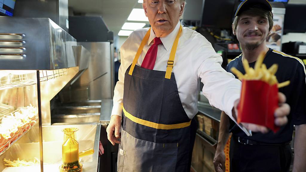 dpatopbilder - Donald Trump (l), Präsidentschaftskandidat der Republikaner und ehemaliger US-Präsident, gibt eine Pommes-Bestellung aus, nachdem er mit einem Angestellten während eines Besuchs bei McDonald's in Feasterville-Trevose zusammengearbeitet hat. Foto: Doug Mills/The New York Times Pool via AP/dpa