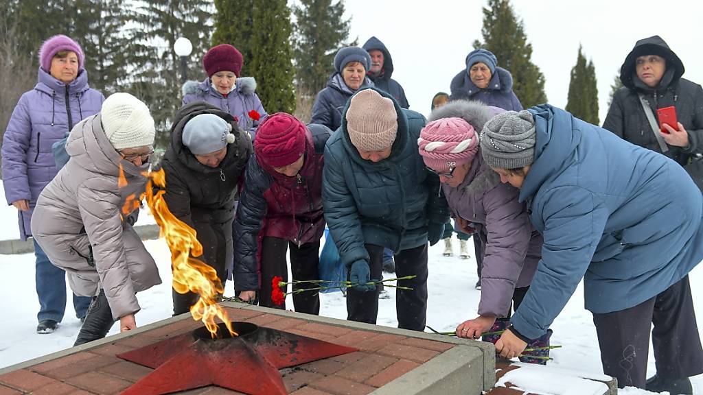 Nach dem Absturz eines russischen Militärtransportflugzeugs legen Frauen in der Grenzregion Belgorod Blumen an einem Gefallenendenkmal nieder. Foto: Uncredited/AP/dpa