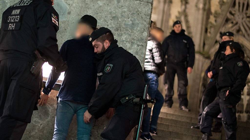 Polizisten durchsuchen einen Verdächtigen beim Kölner Dom. Nach den massenhaften Übergriffen in der Silvesternacht ist die Polizei in die Kritik geraten.