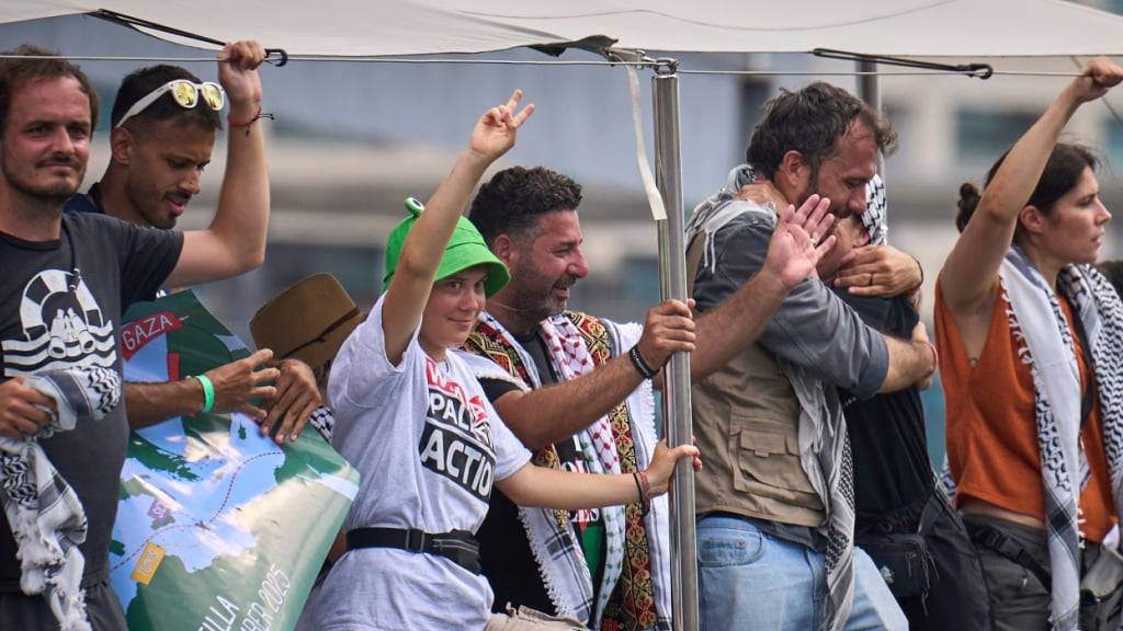Die schwedische Klimaaktivistin Greta Thunberg (M) winkt von einem Boot aus, das an der Global Sumud Flotilla nach Gaza teilnimmt, um die israelische Blockade zu durchbrechen und humanitäre Hilfe zu leisten. Foto: Emilio Morenatti/AP/dpa