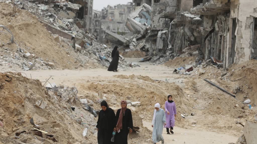 Palästinenser gehen zwischen den beschädigten Gebäuden und Straßen von Chan Junis umher. Foto: Omar Naaman/dpa