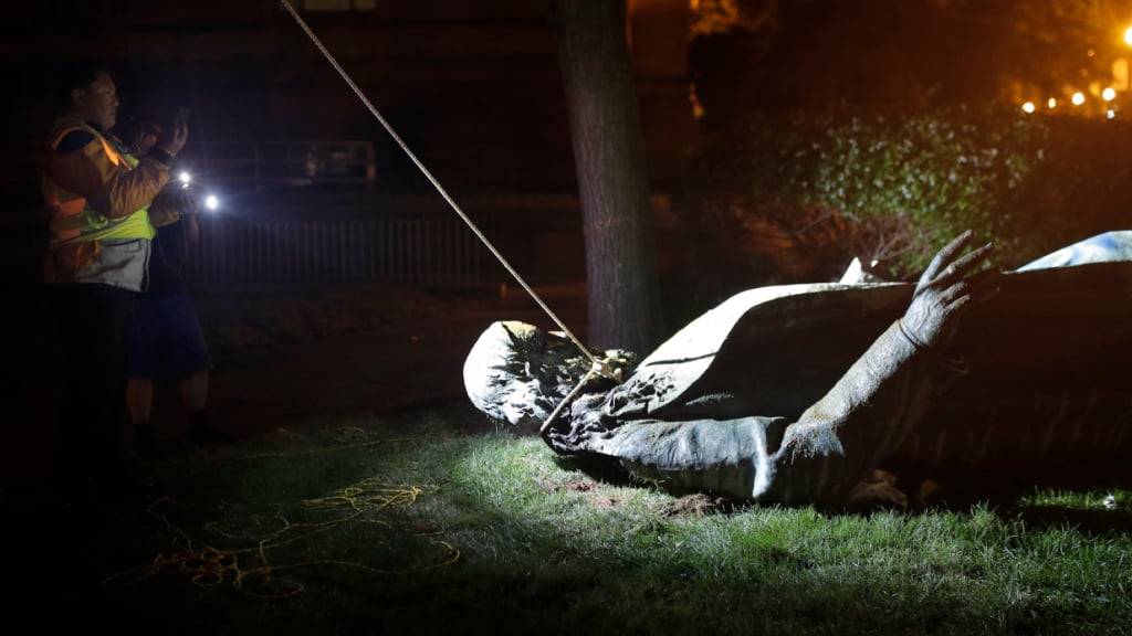 ARCHIV - Menschen machen Fotos von der Statue des Südstaaten-Generals Albert Pike, welche zuvor von Demonstranten gestürzt und in Brand gesteckt worden war. Foto: Maya Alleruzzo/AP/dpa