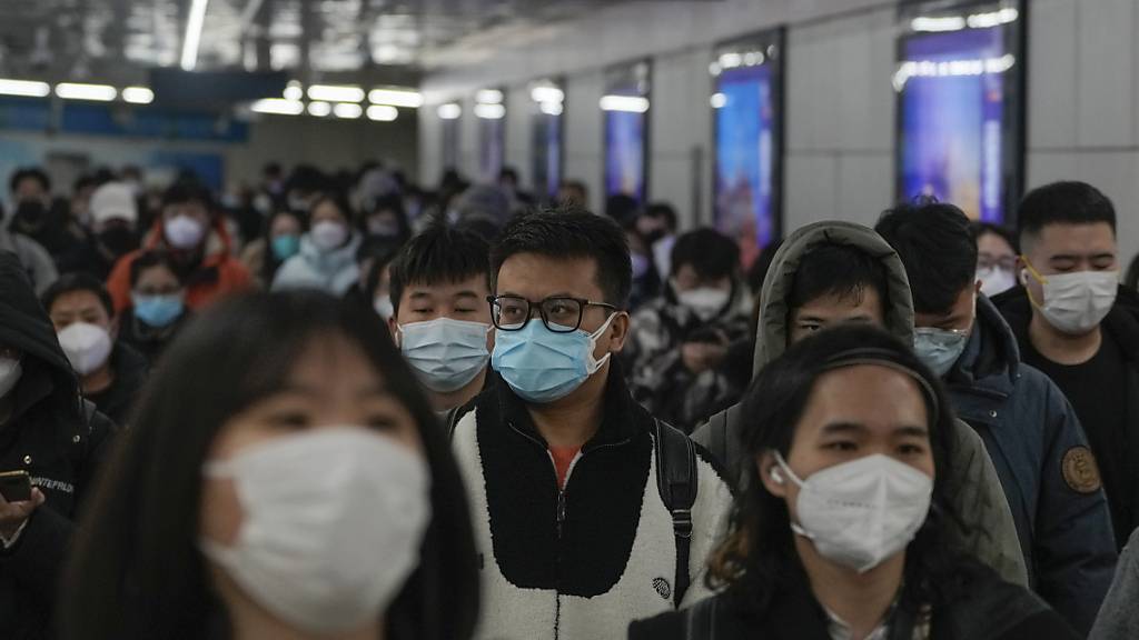 Pendler mit Schutzmasken gehen während des morgendlichen Berufsverkehrs auf dem Weg zur Arbeit in Peking durch einen Gang zwischen zwei U-Bahn-Stationen. China passt sich weiter an die Lockerung der strengen Vorschriften zur Eindämmung des Virus an. Foto: Andy Wong/AP/dpa