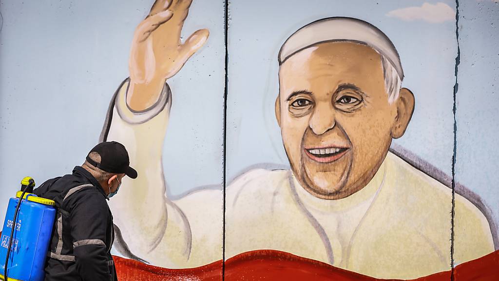 Ein Arbeiter versprüht Desinfektionsmittel an einem Wandgemälde von Papst Franziskus in Bagdad. Foto: Ameer Al Mohammedaw/dpa