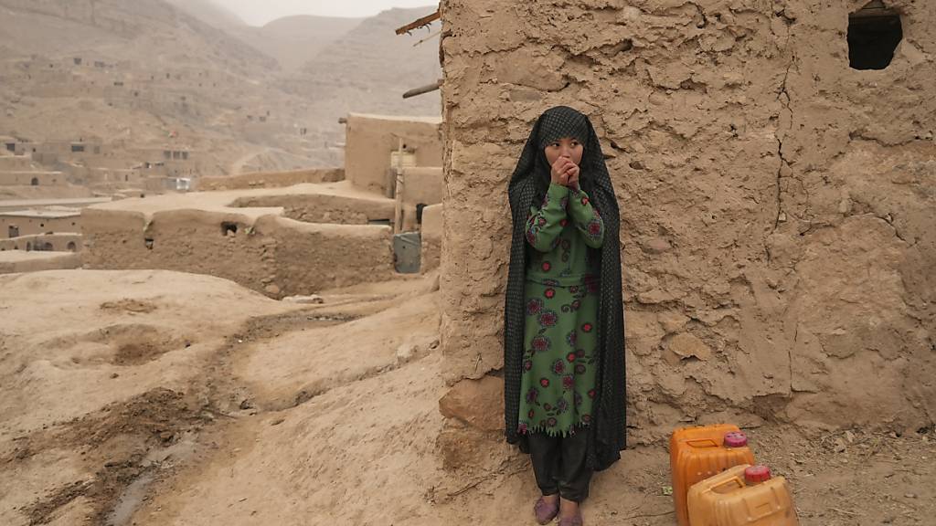 ARCHIV - Ein afghanisches Mädchen wärmt sich die Hände, während es sich vom Wassertragen ausruht. Foto: Mstyslav Chernov/AP/dpa