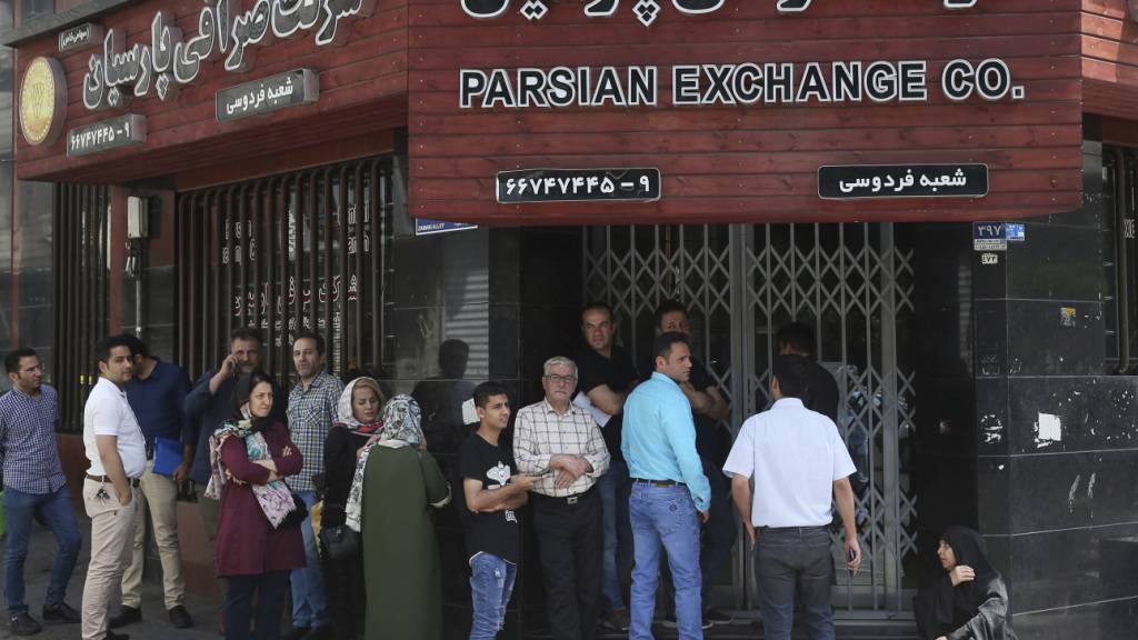 ARCHIV - Menschen stehen vor einer Wechselstube an, um US-Dollar und Euro zu kaufen. Der Iran steckt wegen der von den USA verhängten Sanktionen in einer akuten Währungskrise. Foto: Ebrahim Noroozi/AP/dpa