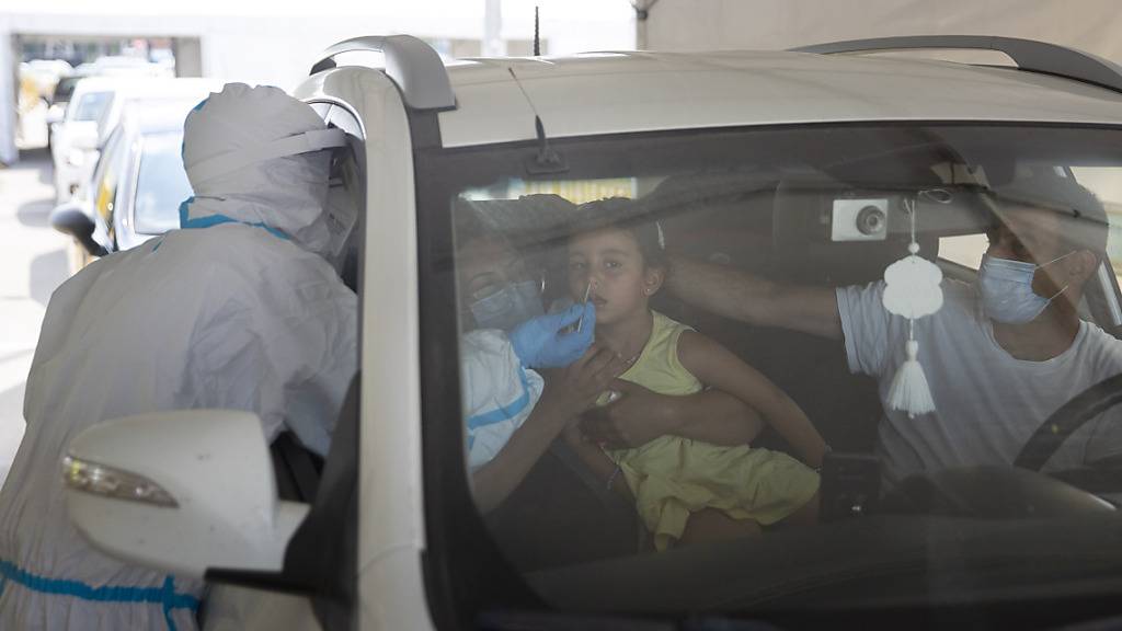 Ein medizinischer Mitarbeiter entnimmt einem Mädchen an einer Drive-Thru-Station für Covid-19-Tests einen Abstrich über die Nase. Nach einem deutlichen Anstieg von Corona-Neuinfektionen hat Israel am Montag die Beschränkungen zur Eindämmung des Virus verschärft. Foto: Sebastian Scheiner/AP/dpa