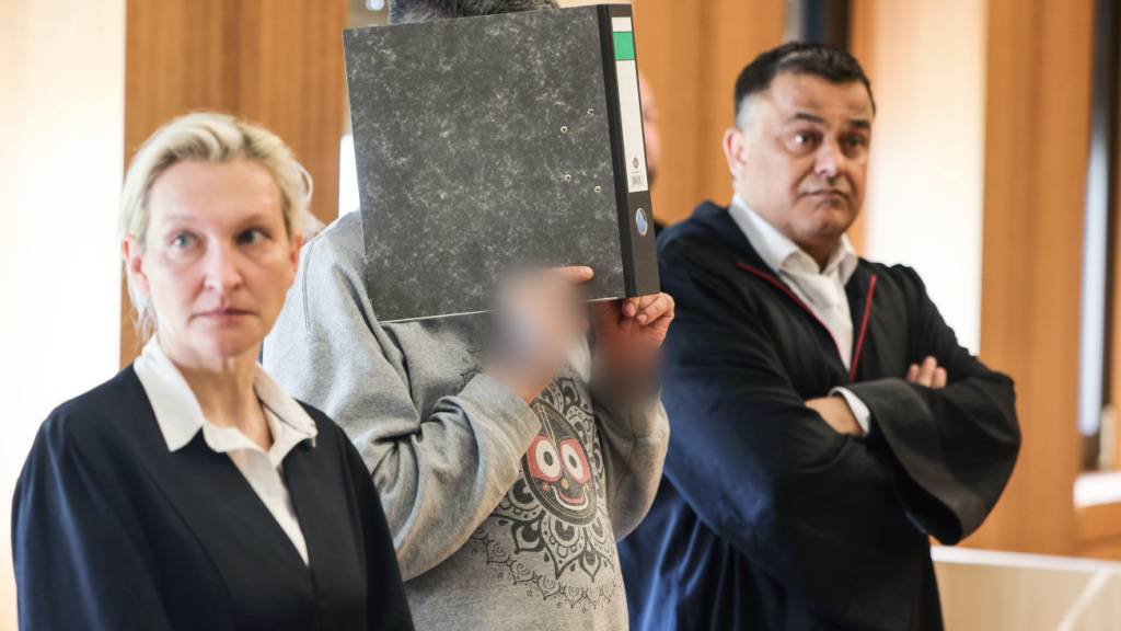 ARCHIV - Der angeklagte Krankenpfleger hält sich zwischen seinen Anwälten Volker Breyer (r) und Tanja Tomasso (l) einen Aktenordner vor das Gesicht. Der Krankenpfleger steht wegen Mordes an neun Patienten vor dem Aachener Landgericht. Foto: Oliver Berg/dpa