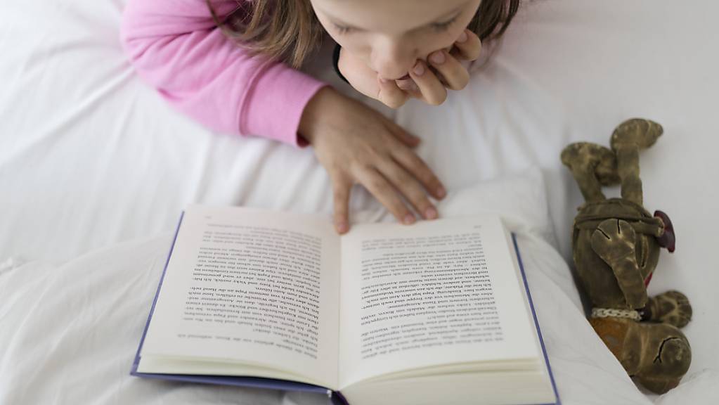 Eine Schlaganfall in der frühen Kindheit verursacht deutlich gravierendere Hirnschäden als im Babyalter oder bei über 6-Jährigen. Das schlägt sich auf die kognitiven Fähigkeiten nieder: ein Mädchen liest ein Buch. (Themenbild)