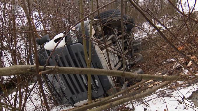 LKW rutscht von Strasse und bleibt auf der Seite liegen