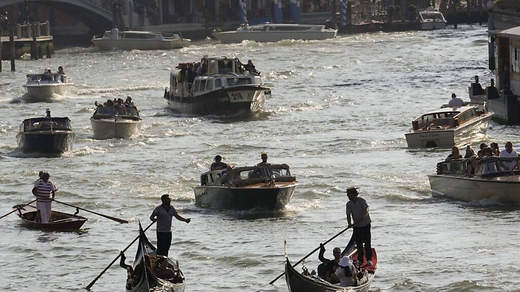 Boote und Gondeln fahren auf einem Kanal. Die UN-Kulturorganisation Unesco hat beschlossen, Venedig und seine Lagune - anders als beabsichtigt - nicht in die Liste des gefährdeten Welterbes aufzunehmen. Foto: Luca Bruno/AP/dpa