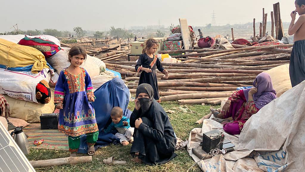 Eine Frau sitzt mit ihren Kindern zwischen den Überresten eines Flüchtlingslagers am Stadtrand von Islamabad, das von Bulldozern abgerissen wurde. Unter dem Druck einer angedrohten Massenabschiebung verlassen Tausende afghanische Flüchtlinge Pakistan in Richtung ihrer Heimat. Foto: Nabila Lalee/dpa