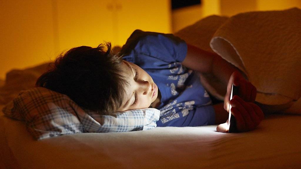 Der abendliche Blick auf das Handydisplay kann die Ausschüttung des schlafanstossenden Hormons Melatonin verzögern. Jugendliche sind deshalb oft nicht genügend ausgeruht. (Symbolbild)