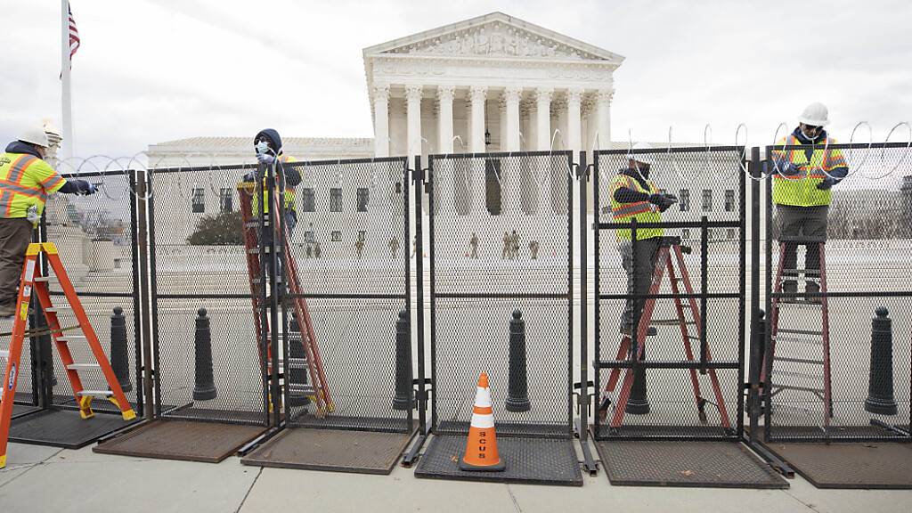 ARCHIV - Arbeiter stehen am Zaun vor dem US-Kapitol während der Sicherheitsvorbereitungen vor der Wiedereröffnung des Gebäudes. Gut acht Monate nach der Erstürmung des Kapitols in Washington bereitet sich die Polizei auf eine weitere Demonstration durch Anhänger des damaligen US-Präsidenten Donald Trump vor. Foto: Mark Finkenstaedt/ZUMA Wire/dpa