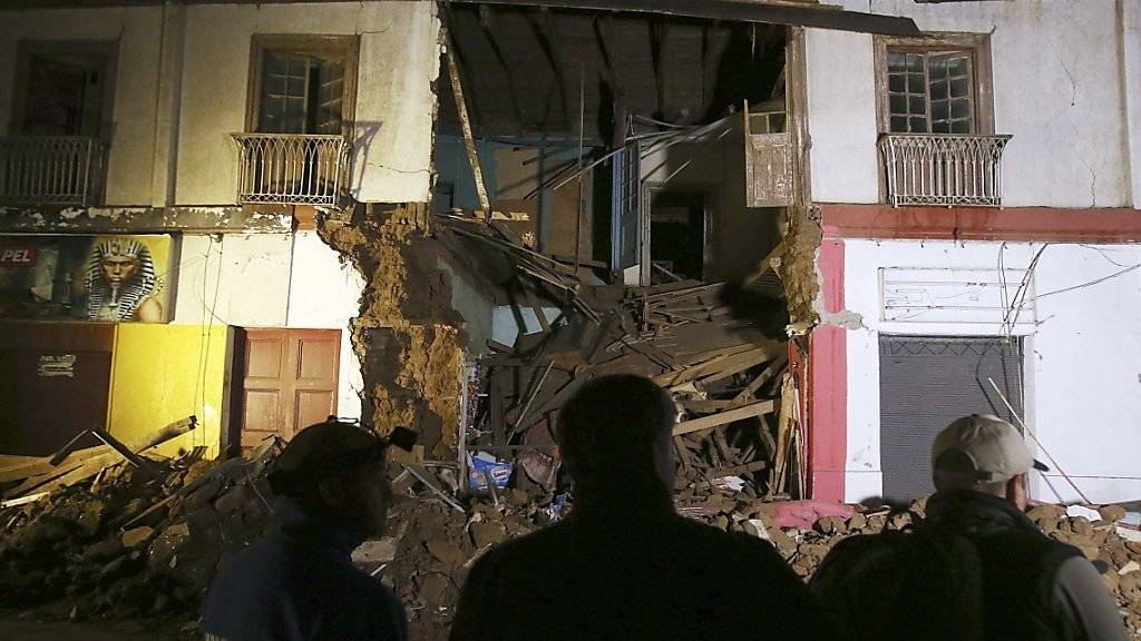 Chilenen vor einem eingestürzten Gebäude in Illapel