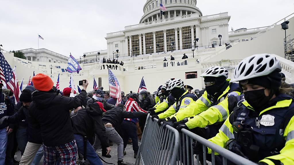 dpatopbilder - Unterstützer des US-Präsidenten Trump versuchen eine Absperrung vor dem Kapitol zu durchbrechen. Foto: John Minchillo/AP/dpa