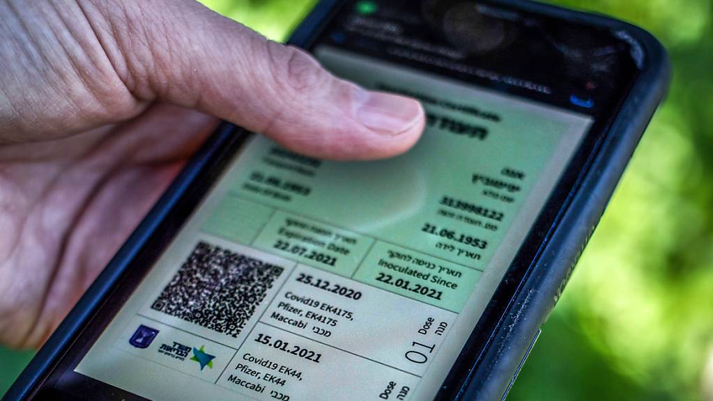 Ein israelischer Mann hält ein Smartphone in der Hand, auf dem der sogenannte «Grüne Pass» abgebildet ist. Angesichts stark ansteigender Corona-Infektionszahlen dehnt Israel die Anwendung des sogenannten Grünen Passes auf fast alle Bereiche des öffentlichen Lebens aus.