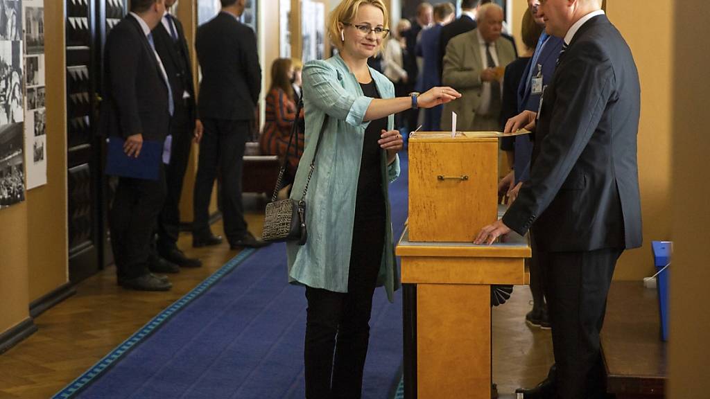 Eine estnische Abgeordnete (M) wirft im estnischen Parlament bei der Wahl über den neuen estnischen Staatspräsidenten ihren Wahlzettel in eine Wahlurne. Einziger Kandidat bei der Abstimmung über das höchste Staatsamt des baltischen EU- und Nato-Landes ist Alar Karis. Foto: Raul Mee/AP/dpa