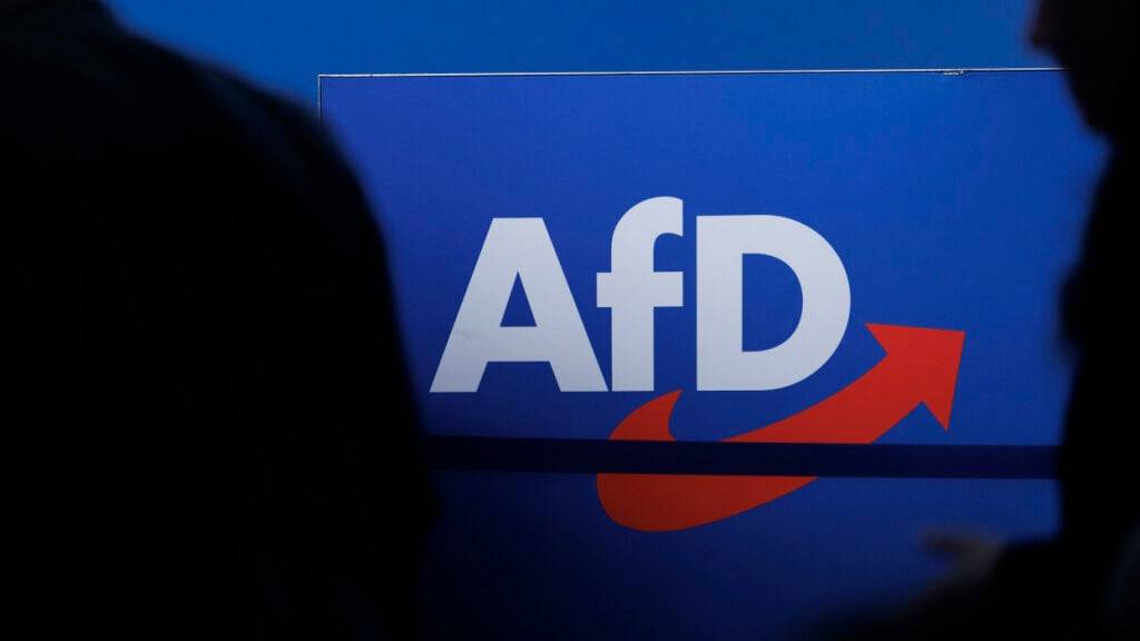 ARCHIV - Delegierte gehen vor dem Parteilogo bei dem AfD-Bundesparteitag in Magdeburg. Foto: Carsten Koall/dpa
