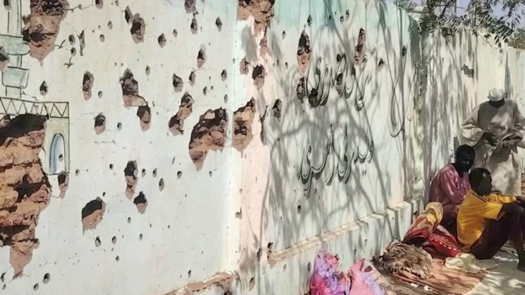 ARCHIV - In diesem Videobild sitzen vertriebene Sudanesen neben einer von Kugeln durchlöcherten Wand und suchen Schutz in einer Schule, nachdem sie von der sudanesischen Armee aus Gebieten evakuiert wurden, die einst von den paramilitärischen Rapid Support Forces (RSF) kontrolliert wurden. Foto: Uncredited/AP/dpa