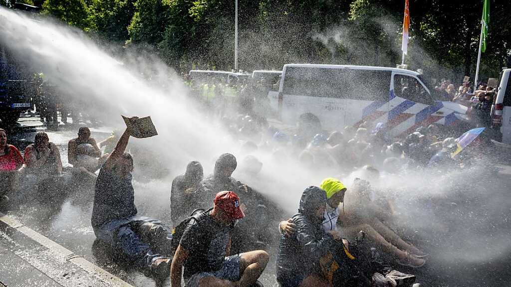 Die Polizei setzt Wasserwerfer gegen Klimaaktivisten ein, die auf der Fahrbahn der A12 demonstrieren. Foto: Robin Utrecht/ANP/dpa