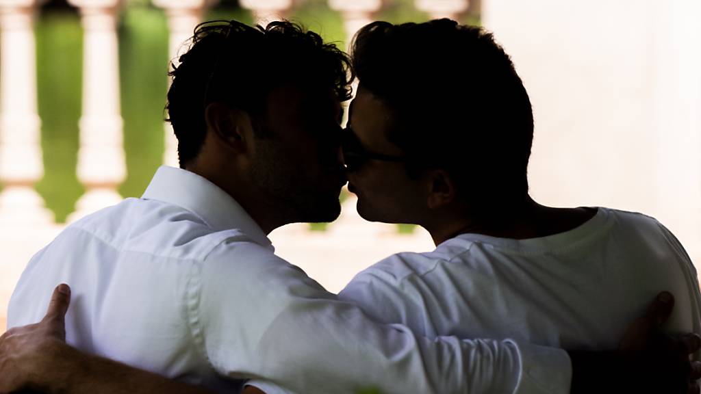 ARCHIV - Zwei Männer sitzen zusammen auf einer Parkbank und küssen sich. Papst Franziskus hat den Weg für die Segnung homosexueller Paare in der katholischen Kirche unter genau festgelegten Bedingungen geebnet. Foto: Mohssen Assanimoghaddam/dpa - ACHTUNG: Nur zur redaktionellen Berichterstattung und Verwendung nur im vollen Format. Keine Bildbearbeitung (Tiefen im Bild dürfen nicht heller gezogen worden, die Männer sollen unkenntlich bleiben).