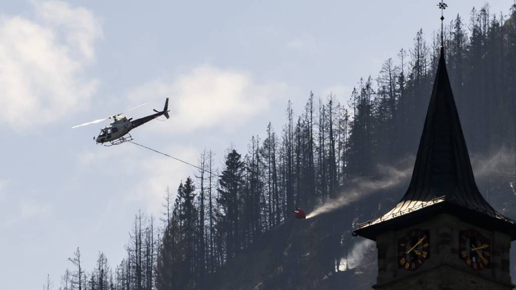 Ein Helikopter der Air Zermatt lässt Wasser über dem Brandgebiet ab.