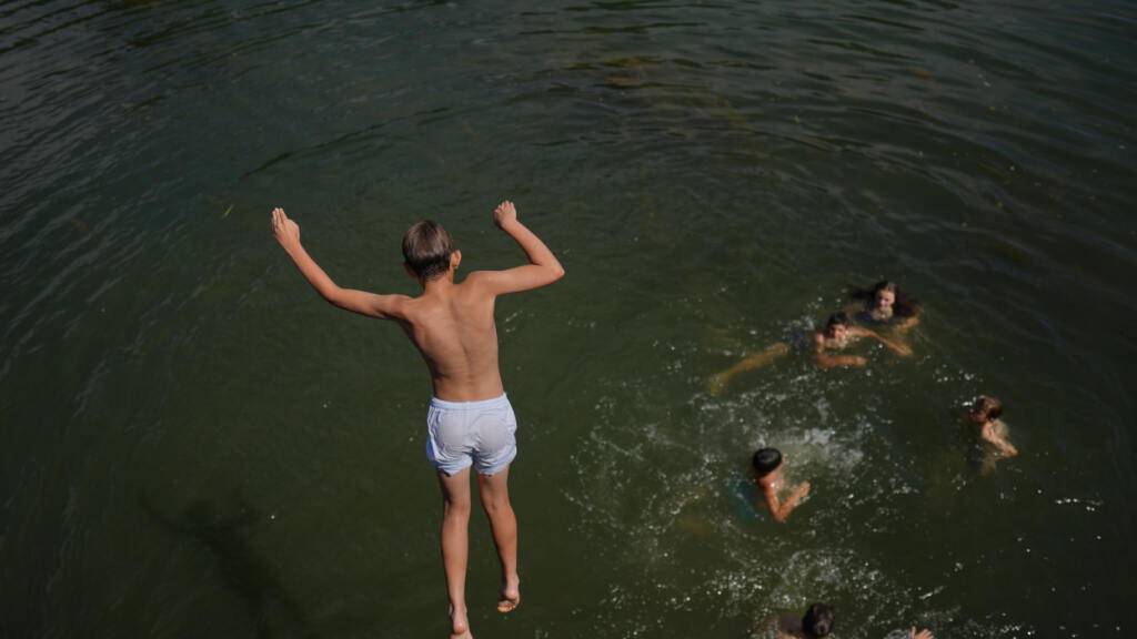Ein Junge springt in die Seine. Foto: Thibault Camus/AP/dpa