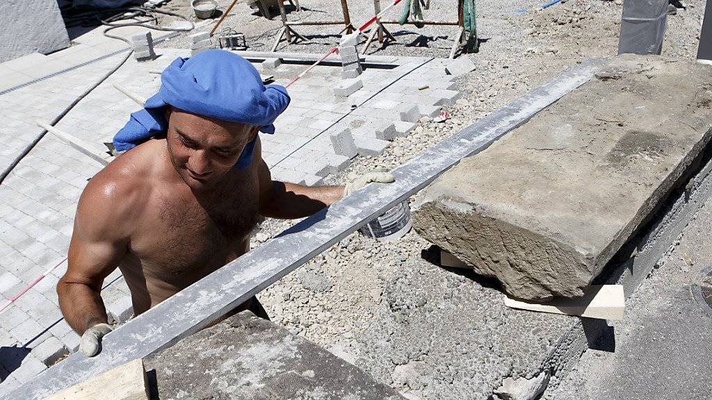 Wegen der Hitze ist die Unfallgefahr grösser als sonst: Ein Bauarbeiter arbeitet in Genf an einer Mauer. (Archivbild)