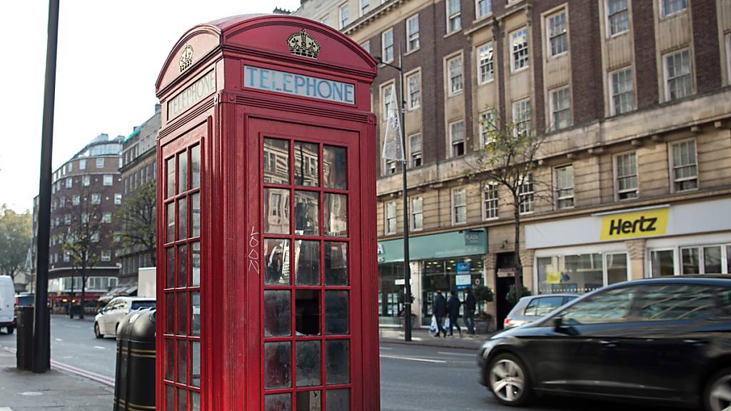 Eine Telefonzelle steht an einem Strassenrand in London. 
