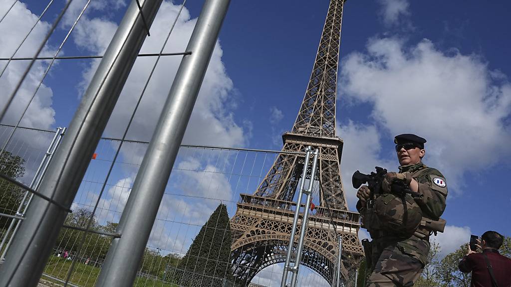 ARCHIV - Ein Soldat patrouilliert an einer Baustelle auf dem Champ-de-Mars, in der Nähe des Eiffelturms, im Vorfeld der Olympischen Spiele 2024 in Paris. Französische Antiterror-Fahnder ermitteln gegen einen Mann mit russischer und ukrainischer Nationalität, der sich bei der Explosion eines selbstgebauten Sprengsatzes in einem Hotel im Umland von Paris schwer verletzt hat. Foto: Laurent Cipriani/AP/dpa