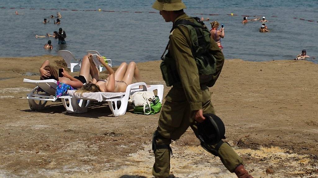 Israelische Soldaten patrouillieren entlang der Küste des Toten Meeres, während Touristinnen am Strand liegen. (Archivbild)