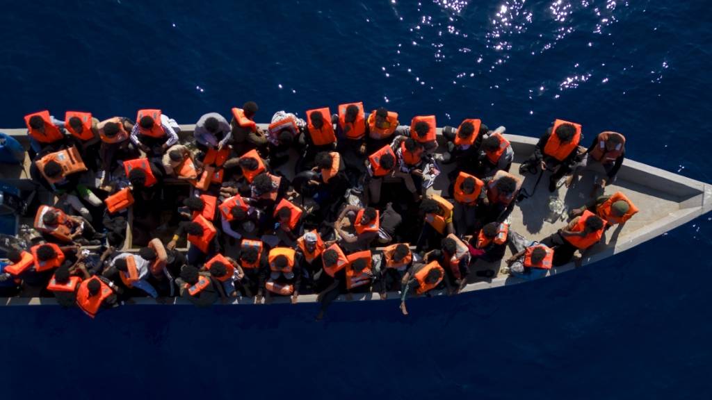 ARCHIV - Aus Eritrea, Libyen und dem Sudan geflüchtete Menschen sitzen in einem Holzboot im Mittelmeer, etwa 30 Meilen nördlich von Libyen. Foto: Joan Mateu Parra/AP/dpa