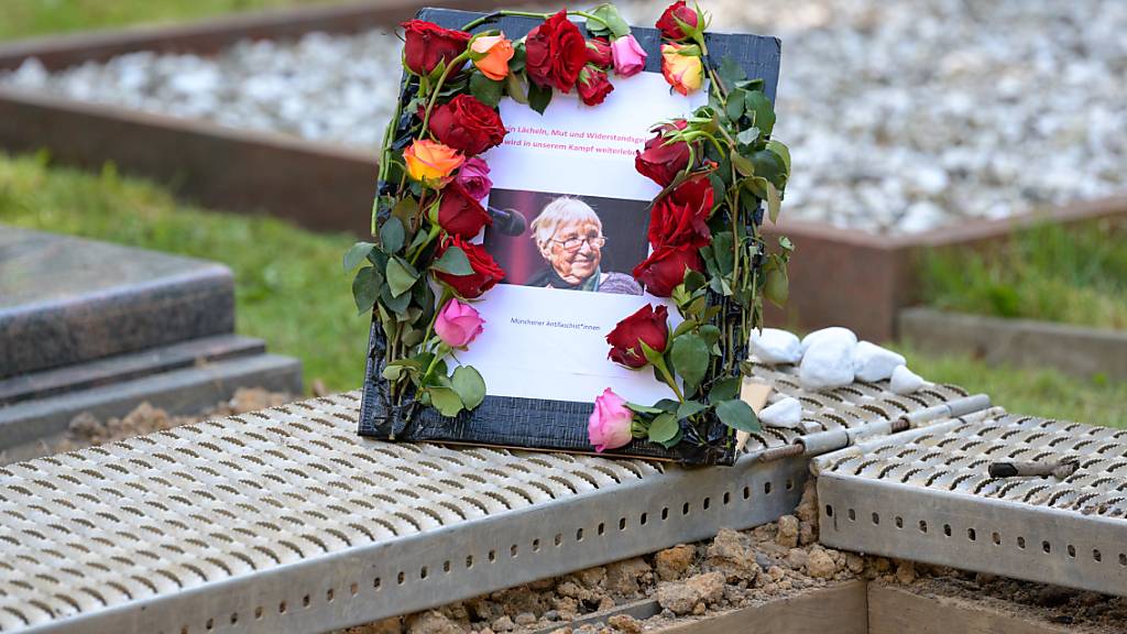 Ein Schild mit einem Foto von Esther Bejarano steht neben ihrem Grab auf dem Jüdischen Friedhof in Hamburg-Ohlsdorf. Die KZ-Überlebende Bejarano ist am Sonntag dort beigesetzt worden. Die Musikerin und Aktivistin war am 10. Juli nach kurzer schwerer Krankheit im Alter von 96 Jahren gestorben. Foto: Jonas Walzberg/dpa-Pool/dpa