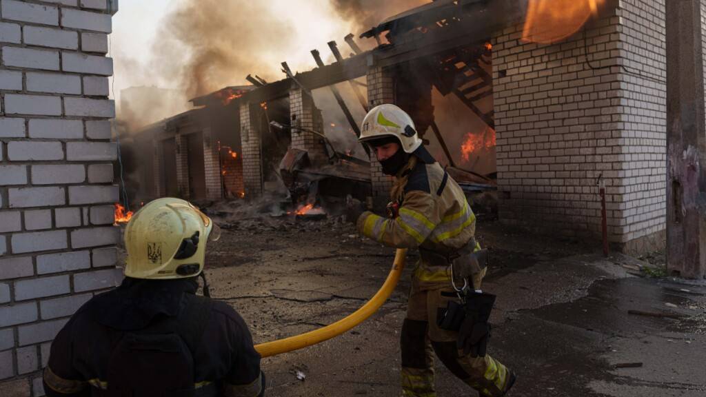 dpatopbilder - Rettungskräfte löschen ein Feuer in einer Autowerkstatt, die durch einen russischen Angriff beschädigt wurde. Foto: Evgeniy Maloletka/AP/dpa