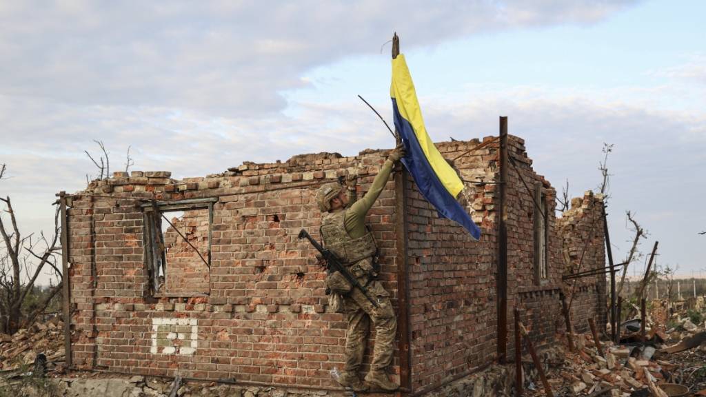 Ein ukrainischer Kommandeur hisst die Nationalflagge als Symbol der Befreiung des Frontdorfes Andrijewka in der Region Donezk. Foto: Alex Babenko/AP/dpa