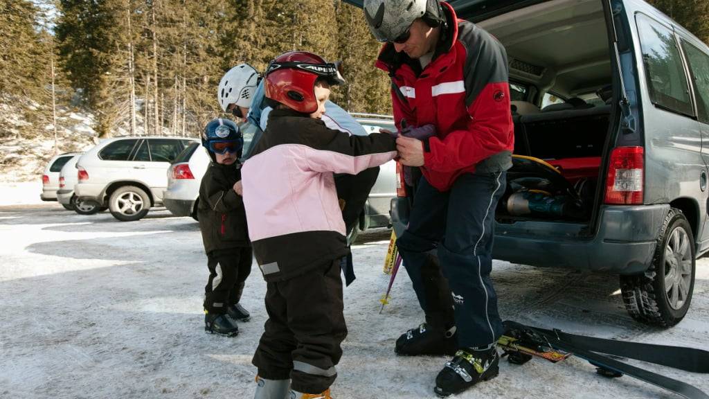 Eine Familie macht sich in Graubünden bereit fürs Skifahren. Schon ab dem nächsten Jahr sollen Bündner Familien von deutlichen Steuersenkungen profitieren. (Archivbild)