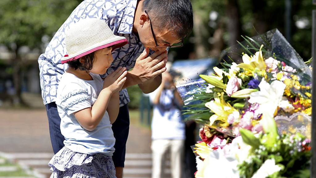 Ein Mann und seine Tochter beten für die Opfer des amerikanischen Atombombenabwurfs vor 75 Jahren. Foto: Takuto Kaneko/Kyodo News/AP/dpa