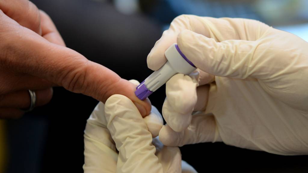 Ein Arzt nimmt bei der Berliner Aids-Hilfe e.v. an dem Finger eines jungen Mannes Blut ab.