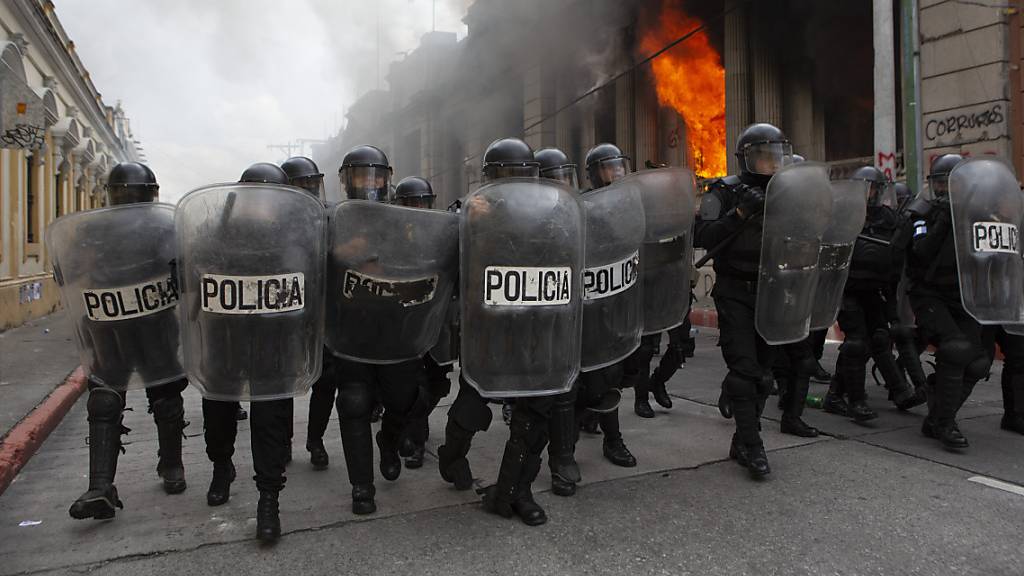 Polizisten bilden eine Blockade gegen Demonstranten. Bei Protesten gegen den Haushalt 2021 haben Demonstranten Teile des Kongresses in Brand gesteckt.