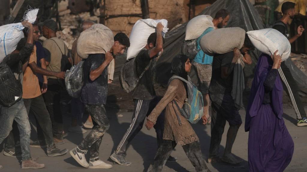 Palästinenser tragen Mehlsäcke, die von einem humanitären Hilfskonvoi geliefert wurden, der Gaza-Stadt aus dem nördlichen Gazastreifen erreichte. Foto: Jehad Alshrafi/AP/dpa