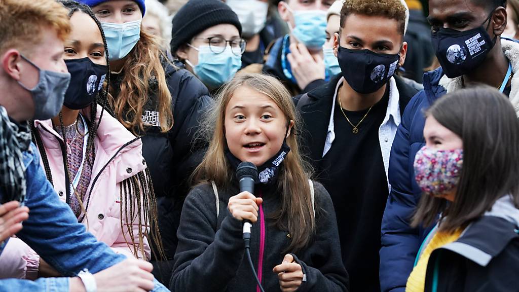 Klimaaktivistin Greta Thunberg (M) spricht in ein Mikrofon, während sie zusammen mit anderen Aktivisten an einer Demonstration am Rande des UN-Klimagipfels COP26 in Glasgow teilnimmt. Foto: Andrew Milligan/PA Wire/dpa