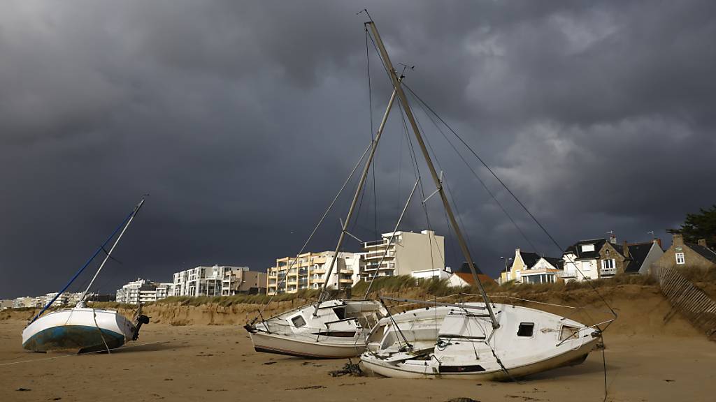Angeschwemmte Boote liegen am Strand in der Bretagne im Sand. Winde mit einer Geschwindigkeit von bis zu 180 Stundenkilometern, heftige Regenfälle und riesige Wellen trafen in der Nacht auf die französische Atlantikküste. Foto: Jeremias Gonzalez/AP/dpa