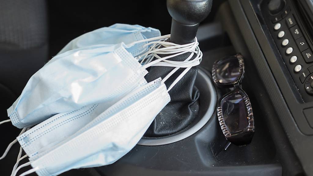 Gesichtsmasken am Schalthebel in einem Auto. (Symbolbild)